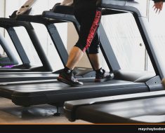 A person walking on a treadmill in a modern gym setting, focusing on fitness.